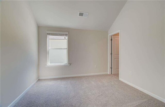 carpeted spare room featuring lofted ceiling