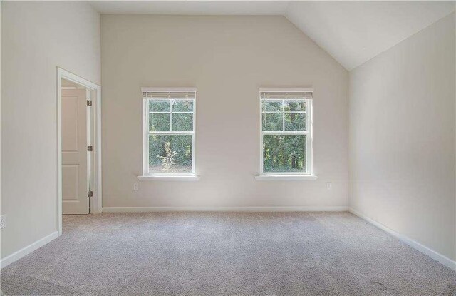 carpeted spare room with lofted ceiling and a wealth of natural light