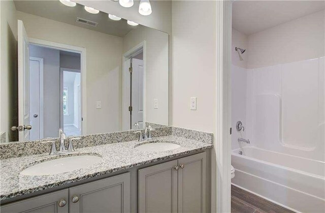 full bathroom with shower / bath combination, vanity, hardwood / wood-style flooring, and toilet