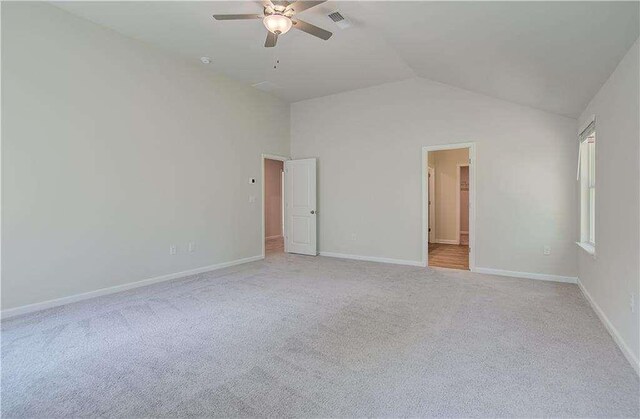 empty room featuring light carpet, ceiling fan, and vaulted ceiling