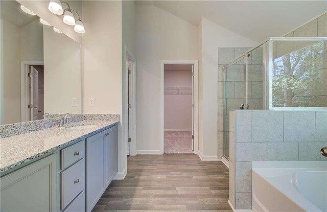 bathroom with vanity, wood-type flooring, shower with separate bathtub, and lofted ceiling