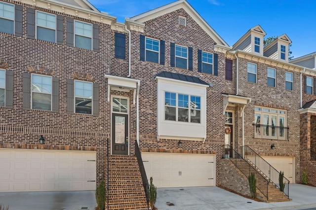 multi unit property with driveway, a garage, and brick siding