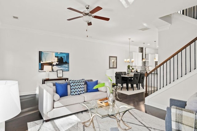 living room with crown molding, visible vents, stairway, wood finished floors, and ceiling fan with notable chandelier