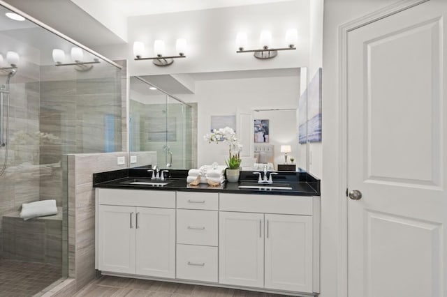 bathroom with a stall shower, a sink, and double vanity