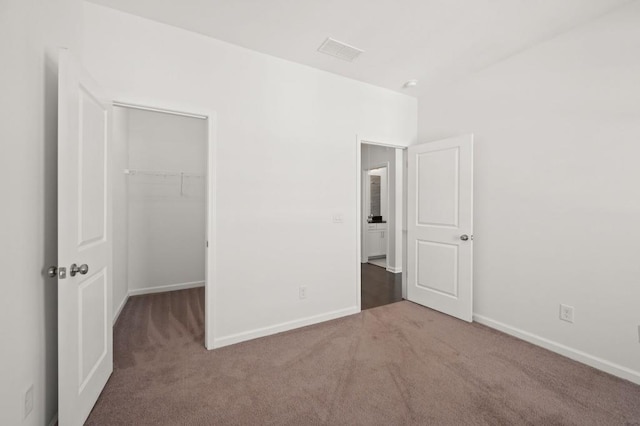 unfurnished bedroom with visible vents, baseboards, a spacious closet, a closet, and carpet