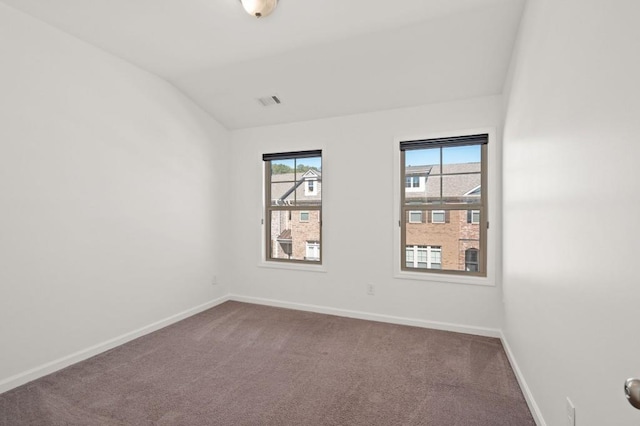 spare room featuring lofted ceiling, carpet flooring, and baseboards