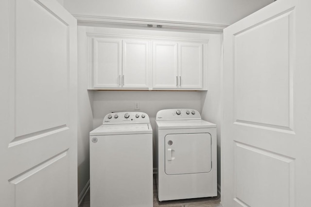 laundry area featuring cabinet space, washing machine and dryer, and wood finished floors