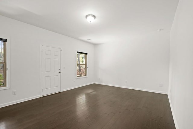 empty room featuring baseboards and dark wood-style flooring