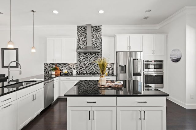 kitchen with a sink, appliances with stainless steel finishes, wall chimney range hood, and crown molding