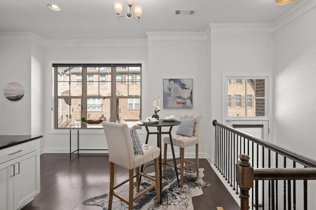 dining room with baseboards, visible vents, dark wood finished floors, crown molding, and a chandelier