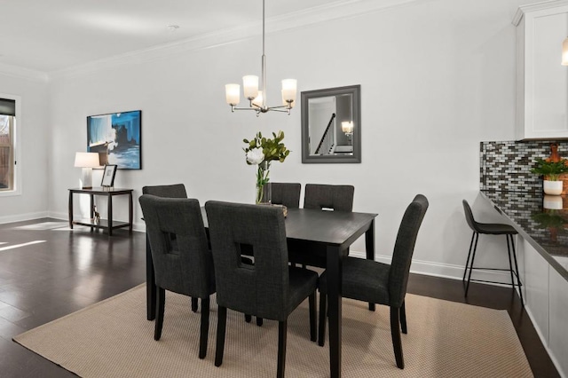 dining area with dark wood-style floors, ornamental molding, a notable chandelier, and baseboards