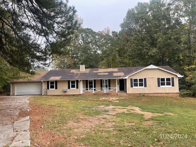 ranch-style home featuring a front lawn, covered porch, and a garage