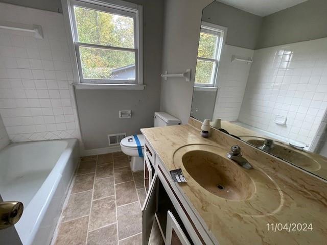 bathroom with tile patterned flooring, vanity, toilet, and a bathing tub