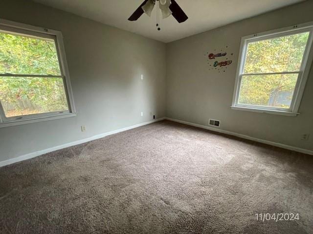 carpeted empty room with ceiling fan and plenty of natural light