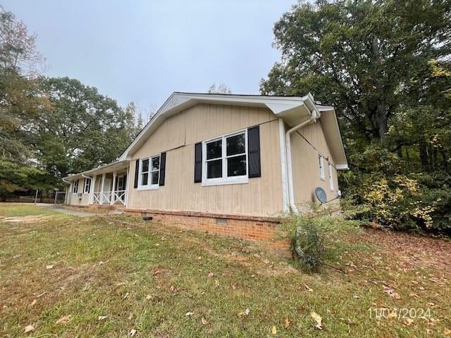 view of side of property featuring a lawn and a porch