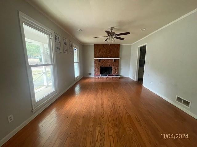 unfurnished living room featuring a fireplace, hardwood / wood-style floors, ceiling fan, and crown molding