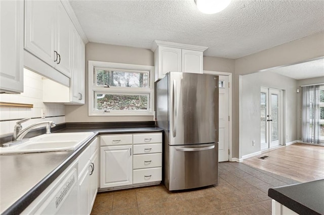 kitchen featuring white cabinets, stainless steel fridge, french doors, and sink