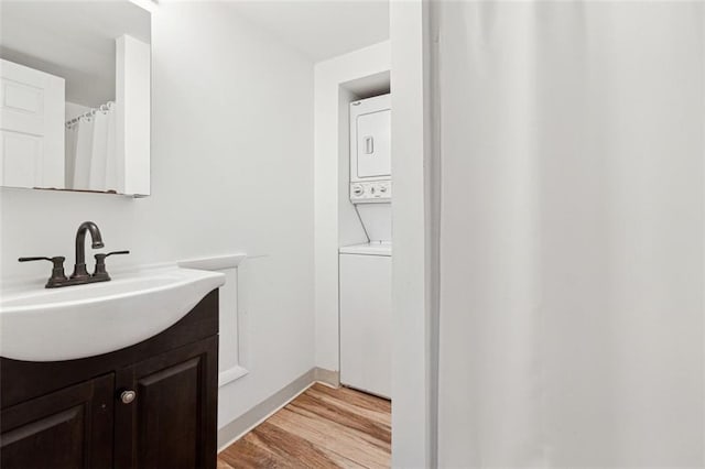 bathroom featuring wood-type flooring, vanity, and stacked washer / drying machine