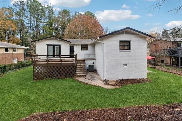 rear view of property featuring a lawn, a wooden deck, and french doors