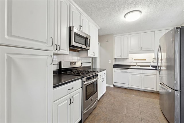 kitchen with backsplash, white cabinets, a textured ceiling, appliances with stainless steel finishes, and light tile patterned flooring