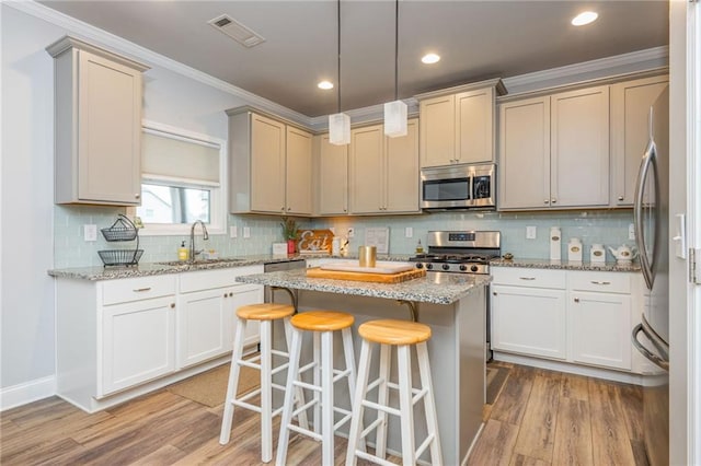 48 Violet Ln, Dallas, GA 30132 - kitchen featuring stainless steel appliances, a sink, light wood finished floors, ornamental molding, and a kitchen breakfast bar