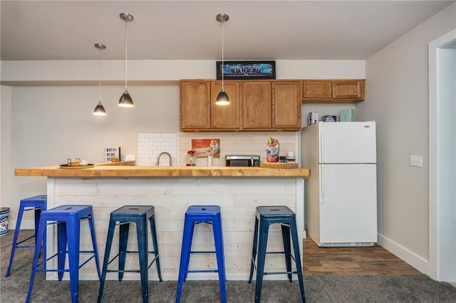 48 Violet Ln, Dallas, GA 30132 - kitchen with freestanding refrigerator, stainless steel microwave, brown cabinets, a breakfast bar area, and hanging light fixtures