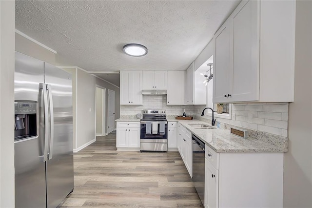 kitchen featuring light stone counters, white cabinets, sink, appliances with stainless steel finishes, and light wood-type flooring