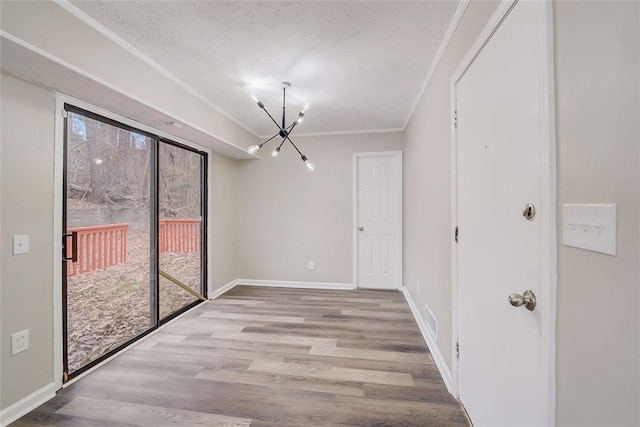 unfurnished dining area with an inviting chandelier, a textured ceiling, crown molding, and light hardwood / wood-style floors