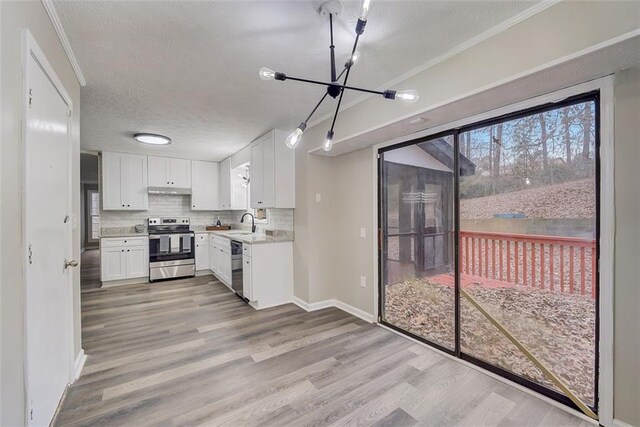 kitchen with stainless steel appliances, white cabinets, tasteful backsplash, and light hardwood / wood-style flooring