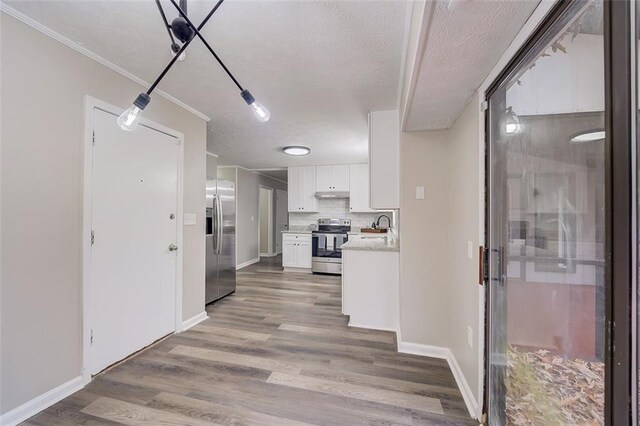 interior space featuring backsplash, stainless steel appliances, white cabinets, hardwood / wood-style flooring, and a textured ceiling