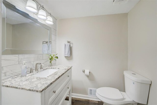 bathroom featuring hardwood / wood-style floors, vanity, toilet, and tasteful backsplash