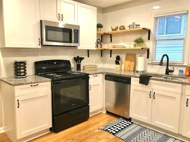 554 Holderness St SW, Atlanta, GA 30310 - kitchen with white cabinets, a sink, light wood-style floors, and appliances with stainless steel finishes