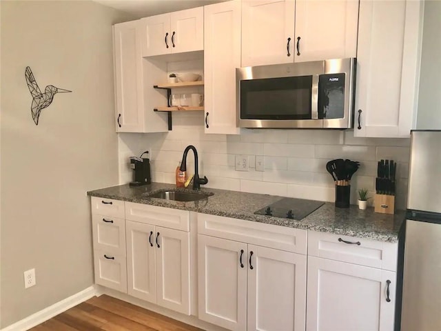 554 Holderness St SW, Atlanta, GA 30310 - kitchen with white cabinets, stainless steel microwave, a sink, black electric stovetop, and backsplash