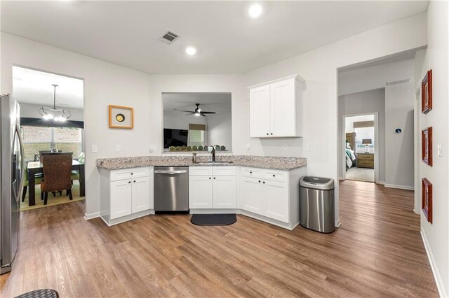 kitchen with white cabinets, light stone countertops, light hardwood / wood-style flooring, appliances with stainless steel finishes, and ceiling fan with notable chandelier