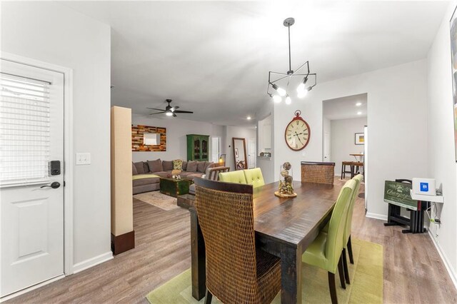 dining room featuring ceiling fan with notable chandelier and light wood-type flooring