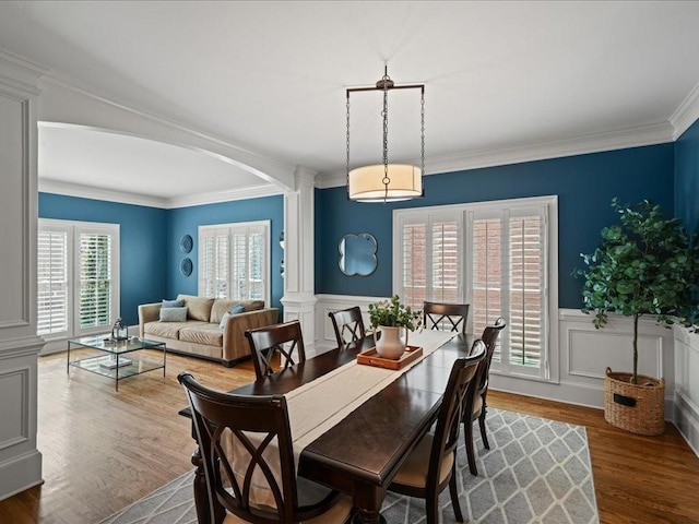 dining room featuring hardwood / wood-style floors, ornamental molding, and ornate columns