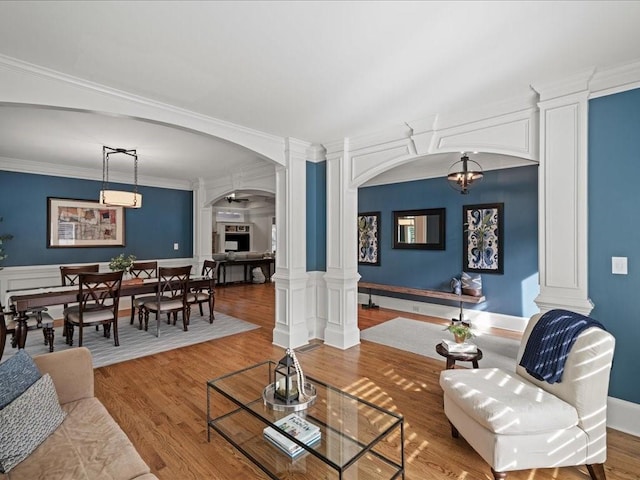 living room with ornate columns, crown molding, and hardwood / wood-style floors