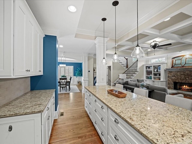 kitchen featuring white cabinetry, hanging light fixtures, light stone countertops, and light wood-type flooring