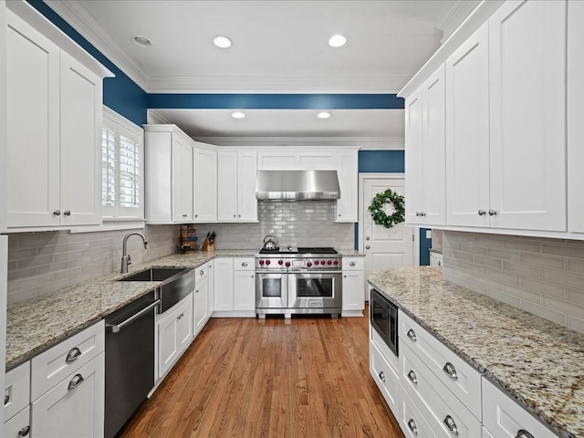 kitchen with sink, white cabinetry, stainless steel appliances, ornamental molding, and light stone countertops