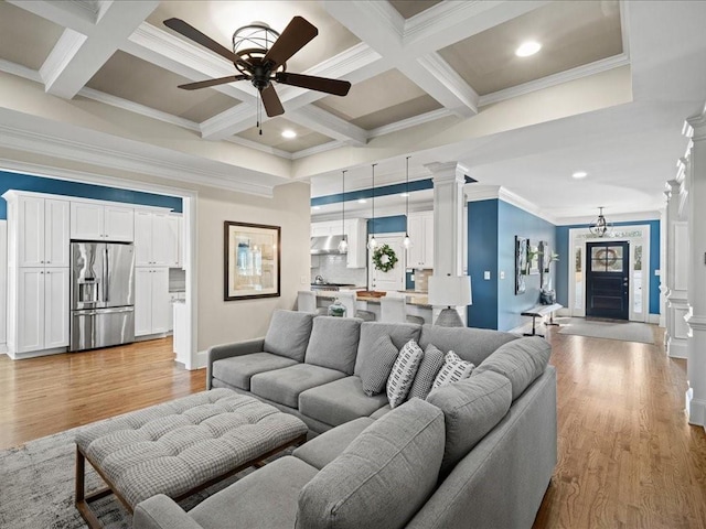 living room featuring crown molding, beam ceiling, light hardwood / wood-style floors, and ornate columns