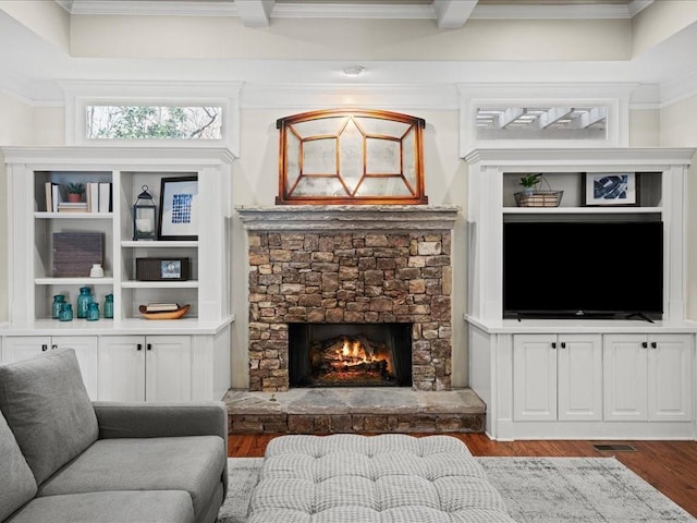 living room with hardwood / wood-style flooring, a fireplace, built in features, and crown molding