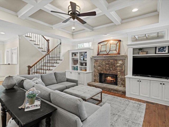 living room with dark wood-type flooring, coffered ceiling, crown molding, beamed ceiling, and a fireplace