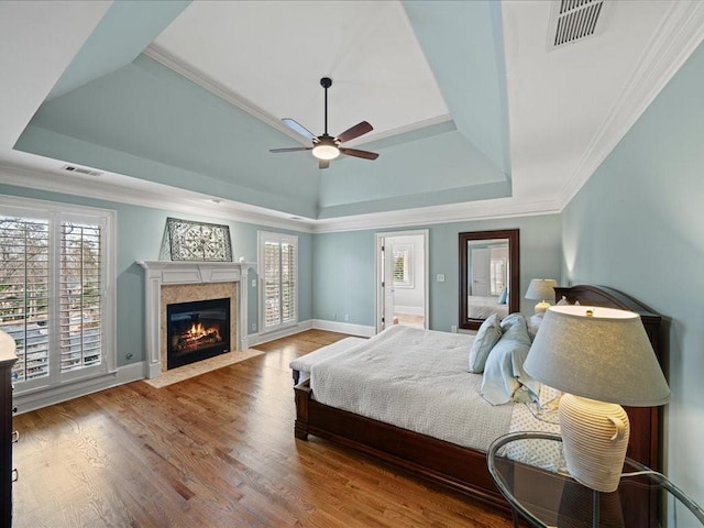 bedroom with a tray ceiling, hardwood / wood-style floors, and multiple windows