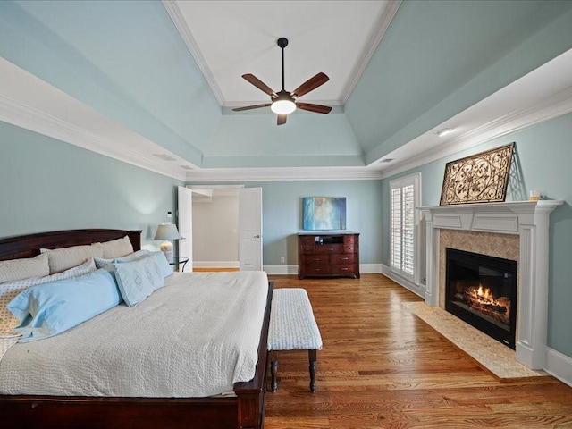 bedroom with hardwood / wood-style flooring, crown molding, ceiling fan, and a tray ceiling