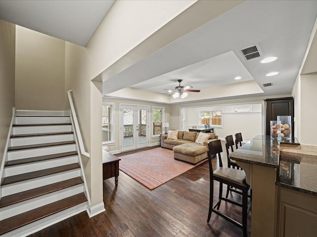 living room with french doors, dark wood-type flooring, ceiling fan, and a tray ceiling