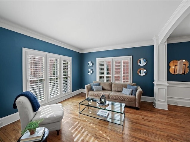 living room featuring crown molding, wood-type flooring, and decorative columns