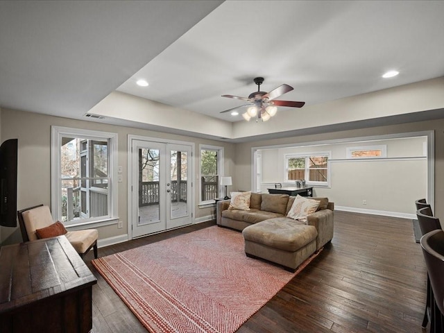 living room featuring a raised ceiling, dark wood-type flooring, ceiling fan, and french doors