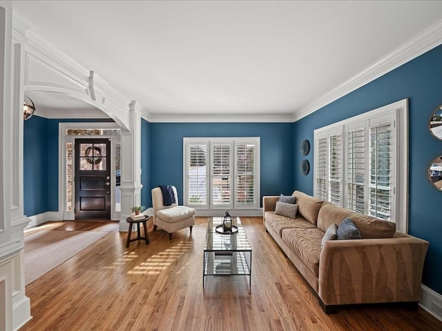 living room featuring ornate columns, ornamental molding, and light wood-type flooring