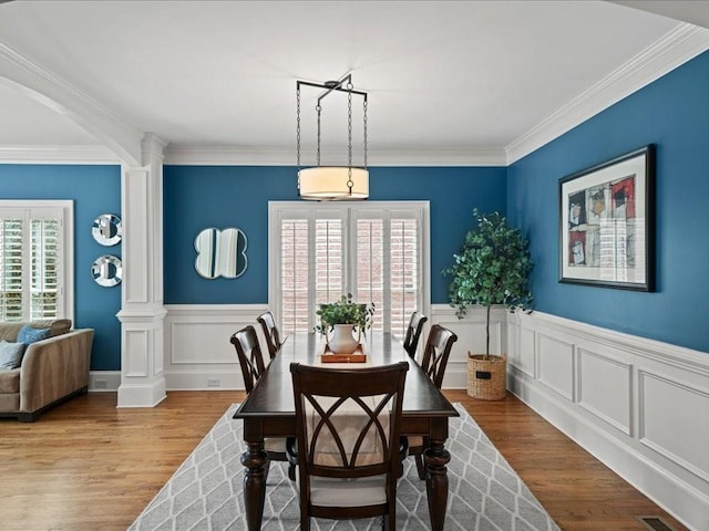 dining room with decorative columns, ornamental molding, and light hardwood / wood-style floors