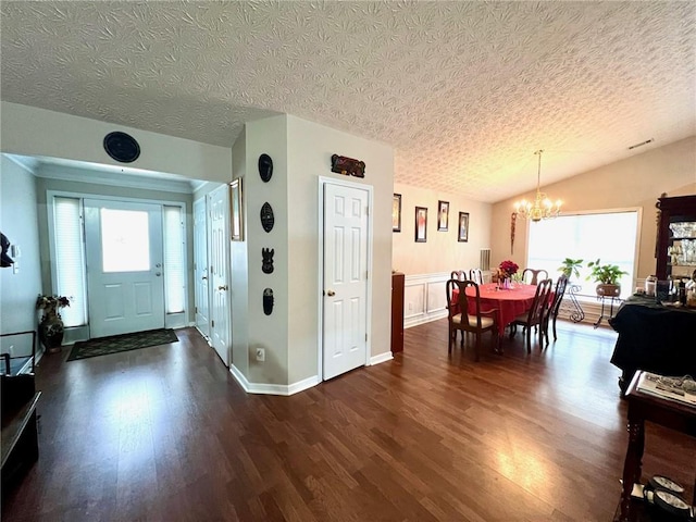 entryway with a notable chandelier, vaulted ceiling, dark hardwood / wood-style floors, and a textured ceiling